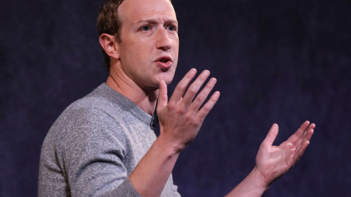 Meta Platforms CEO Mark Zuckerberg, wearing a gray sweater, puts his hands up during a presentation.