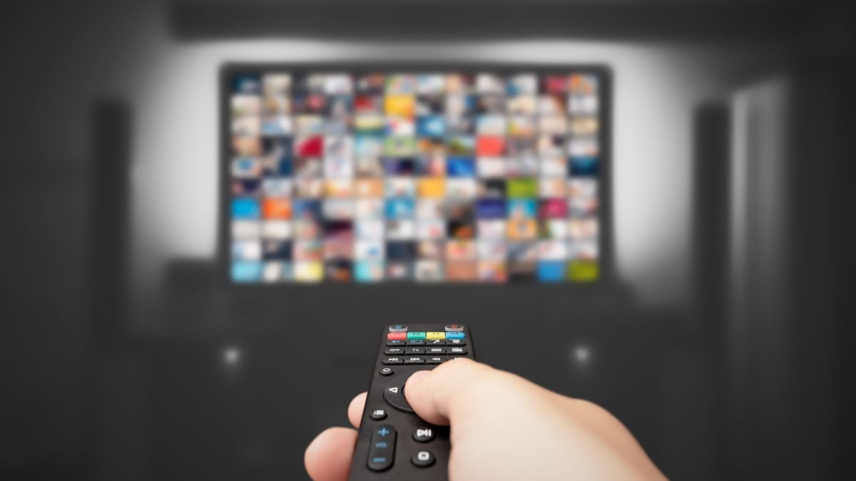 A TV remote points up at a blurred-out screen.