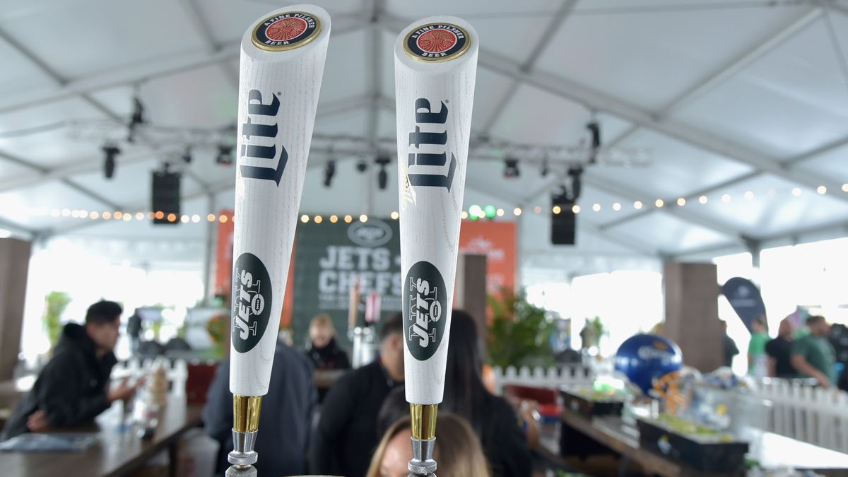 Two white Miller Lite draft handles with the JETS team logo on display at a tailgate party.